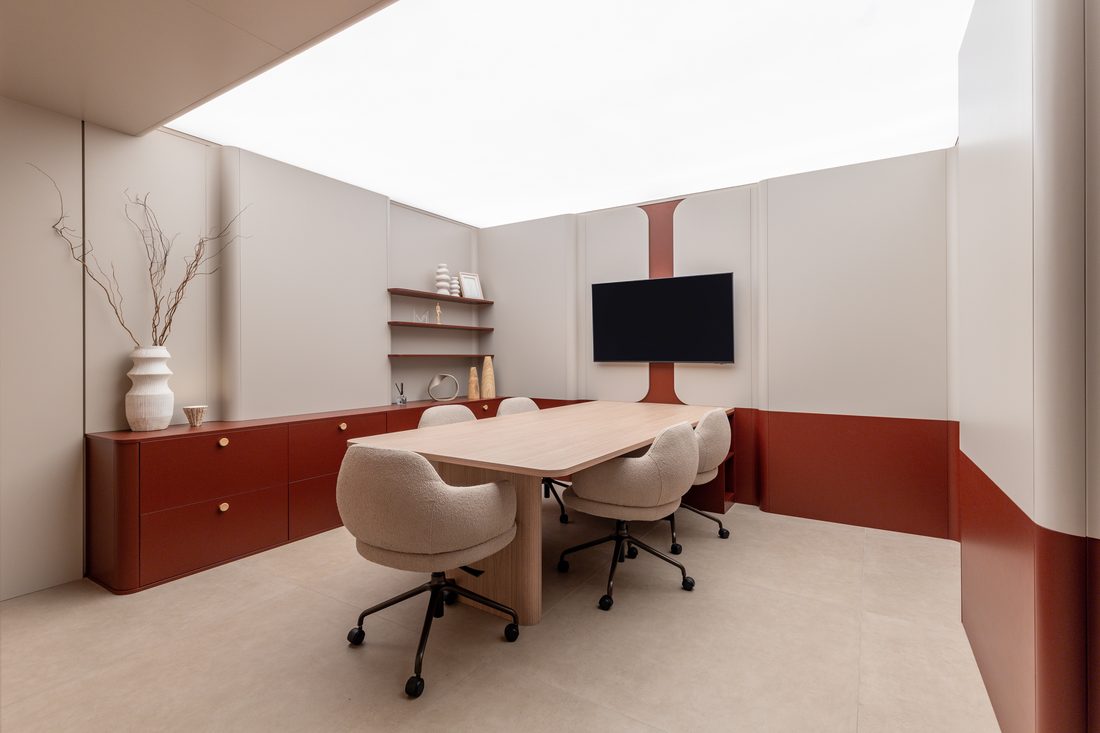 Sala de reunião com armários baixos em laca bordô, prateleiras em balanço e mesa em madeira, projeto Marel