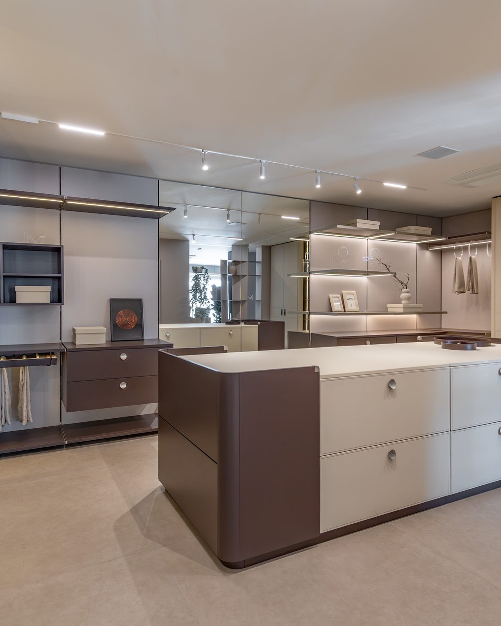 Closet planejado com ilha central, gavetas em couro e iluminação embutida da Marel