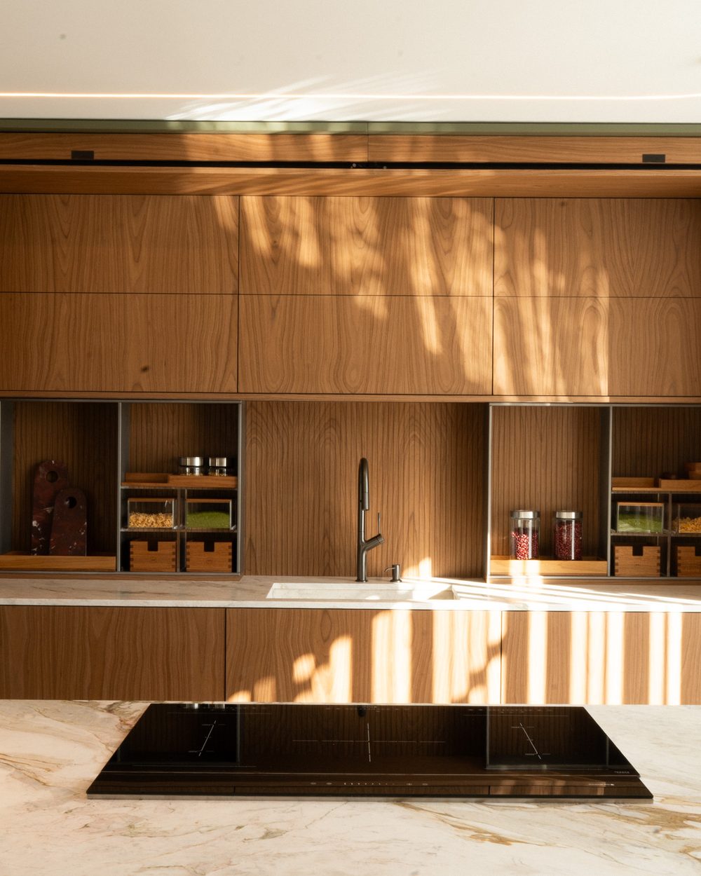 Cozinha planejada com ilha em mármore e cooktop integrado, projeto Marel na Casa Marel